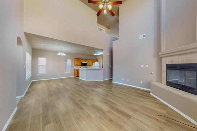 unfurnished living room featuring light wood-style floors, baseboards, visible vents, and a tile fireplace