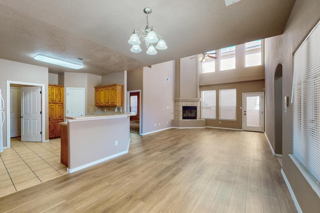 kitchen with light wood-style flooring, light countertops, a tiled fireplace, and open floor plan