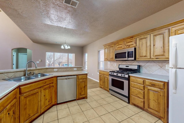 kitchen featuring stainless steel appliances, light countertops, visible vents, decorative backsplash, and a sink