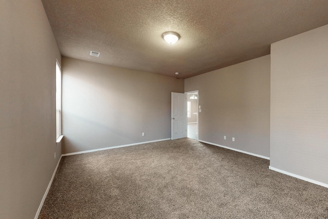 carpeted empty room with a textured ceiling, visible vents, and baseboards