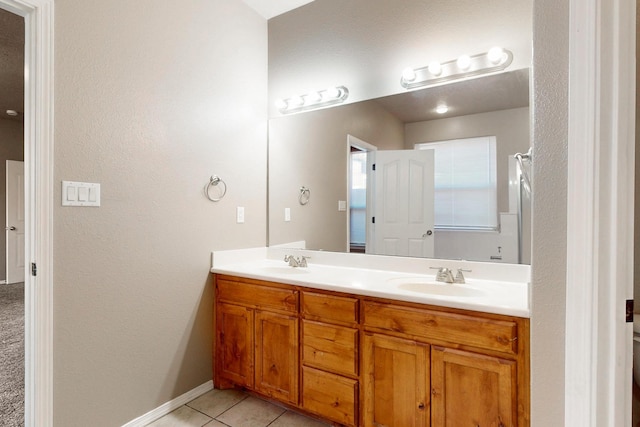 bathroom featuring double vanity, a sink, baseboards, and tile patterned floors