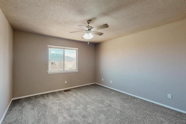 spare room featuring visible vents, baseboards, a ceiling fan, carpet, and a textured ceiling