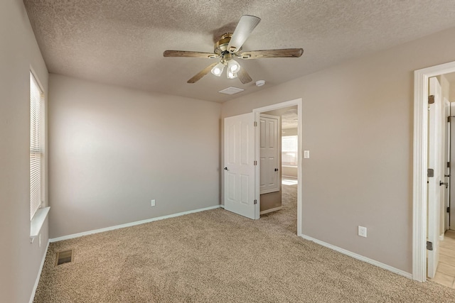 unfurnished bedroom featuring light colored carpet, visible vents, a textured ceiling, and baseboards