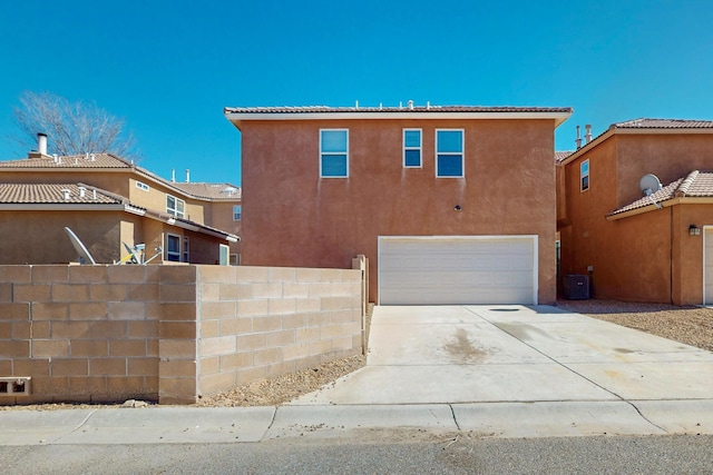 view of front of house featuring a garage, fence, concrete driveway, and stucco siding