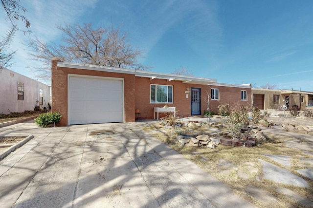 ranch-style home with a garage, concrete driveway, and stucco siding