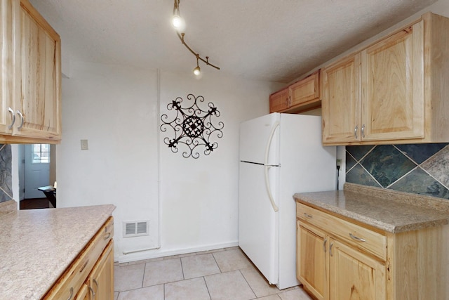 kitchen with visible vents, decorative backsplash, and light brown cabinetry