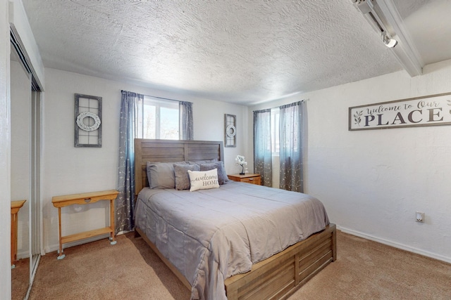 bedroom with light carpet, baseboards, a textured ceiling, and beamed ceiling