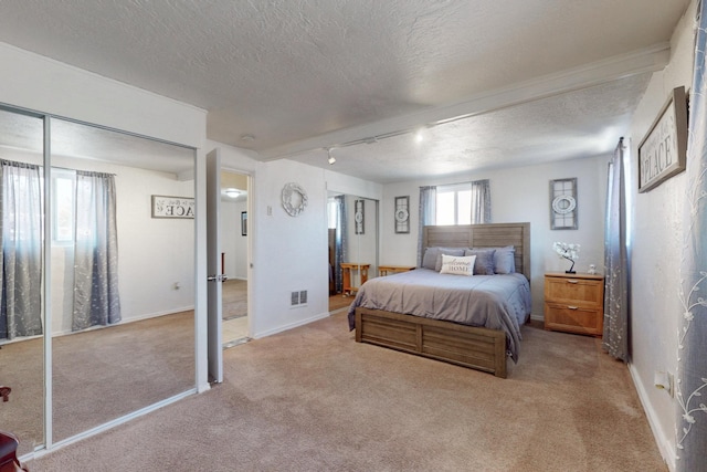 carpeted bedroom with visible vents, baseboards, and a textured ceiling