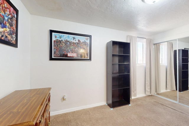 unfurnished office with carpet floors, baseboards, and a textured ceiling