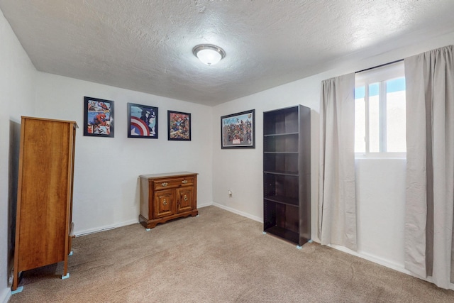 bedroom featuring light carpet, a textured ceiling, and baseboards