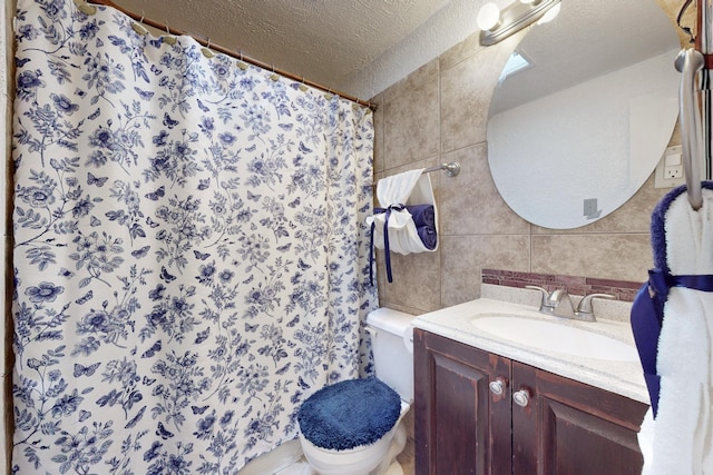 full bath with a textured ceiling, toilet, vanity, and tile walls