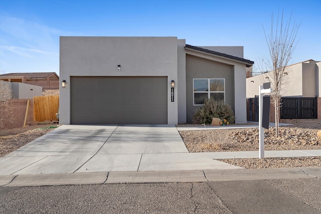 view of front of home with driveway, an attached garage, fence, and stucco siding