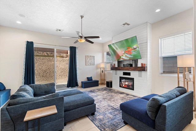 living room featuring a large fireplace, a textured ceiling, visible vents, and recessed lighting