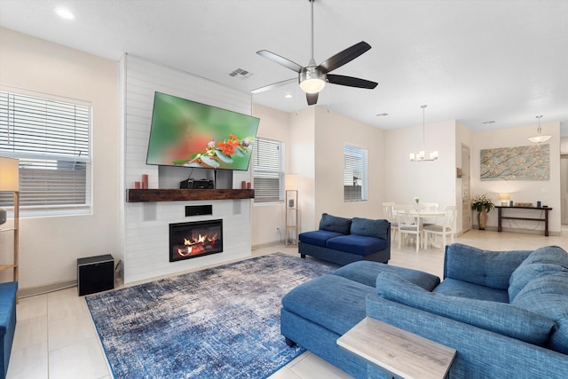 living area featuring tile patterned floors, a fireplace, visible vents, and ceiling fan with notable chandelier