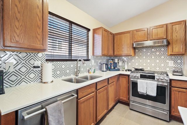 kitchen with lofted ceiling, appliances with stainless steel finishes, light countertops, under cabinet range hood, and a sink