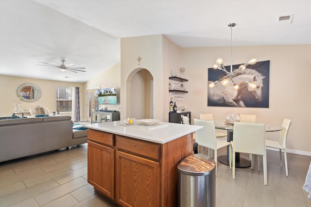 kitchen featuring arched walkways, visible vents, a kitchen island, vaulted ceiling, and ceiling fan with notable chandelier