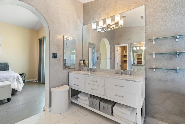 full bath featuring double vanity, baseboards, ensuite bath, a chandelier, and a sink