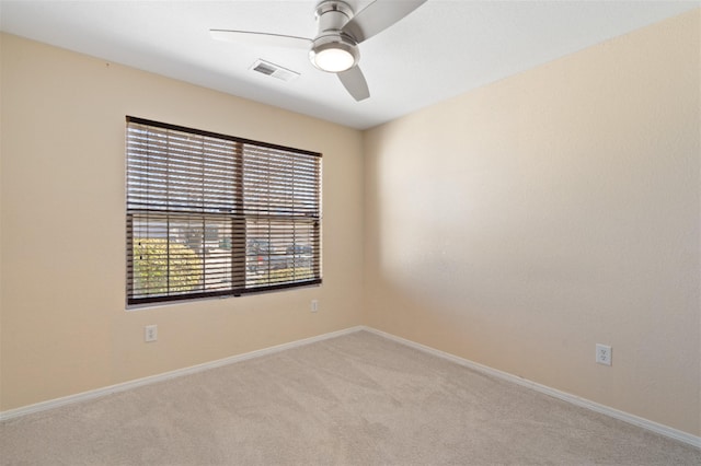 spare room featuring light carpet, a ceiling fan, visible vents, and baseboards