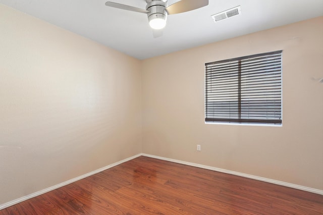 empty room with a ceiling fan, baseboards, visible vents, and wood finished floors