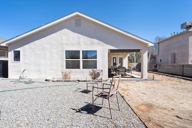 back of property featuring french doors, a patio area, fence, and stucco siding