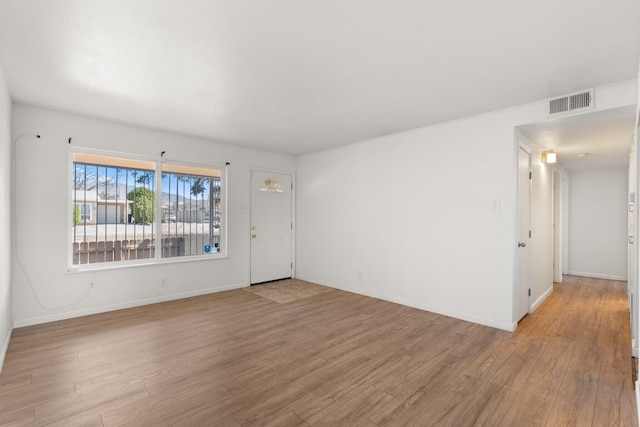 empty room with light wood-type flooring, baseboards, and visible vents