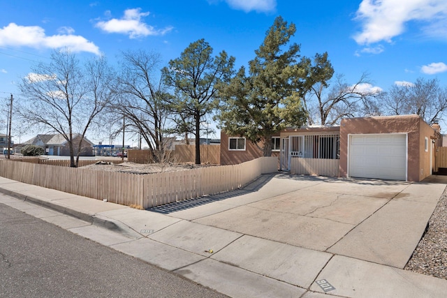 view of front facade featuring an attached garage, a fenced front yard, concrete driveway, and stucco siding