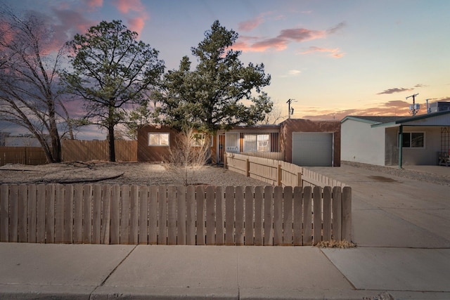 view of front of home with a garage, a fenced front yard, and concrete driveway