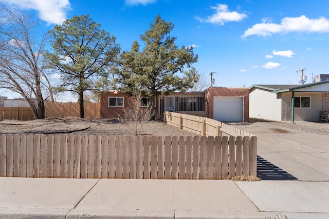 ranch-style house featuring a fenced front yard, driveway, a garage, and stucco siding