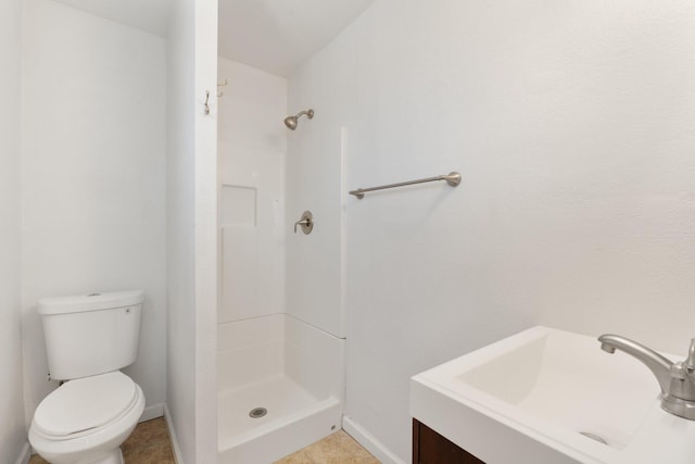 bathroom featuring baseboards, a sink, a shower stall, and toilet