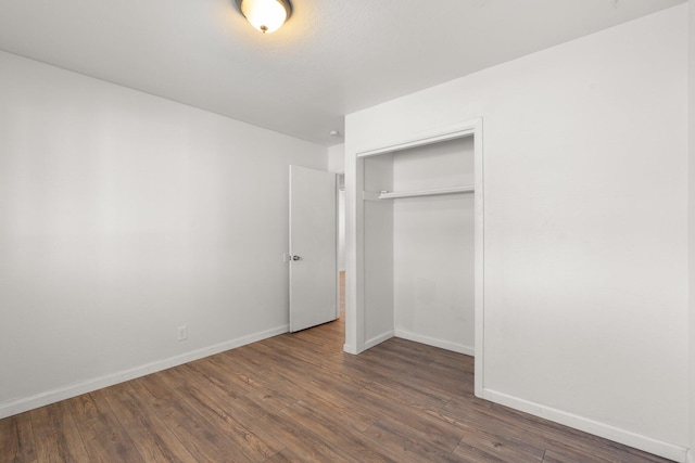 unfurnished bedroom with a closet, baseboards, and wood finished floors