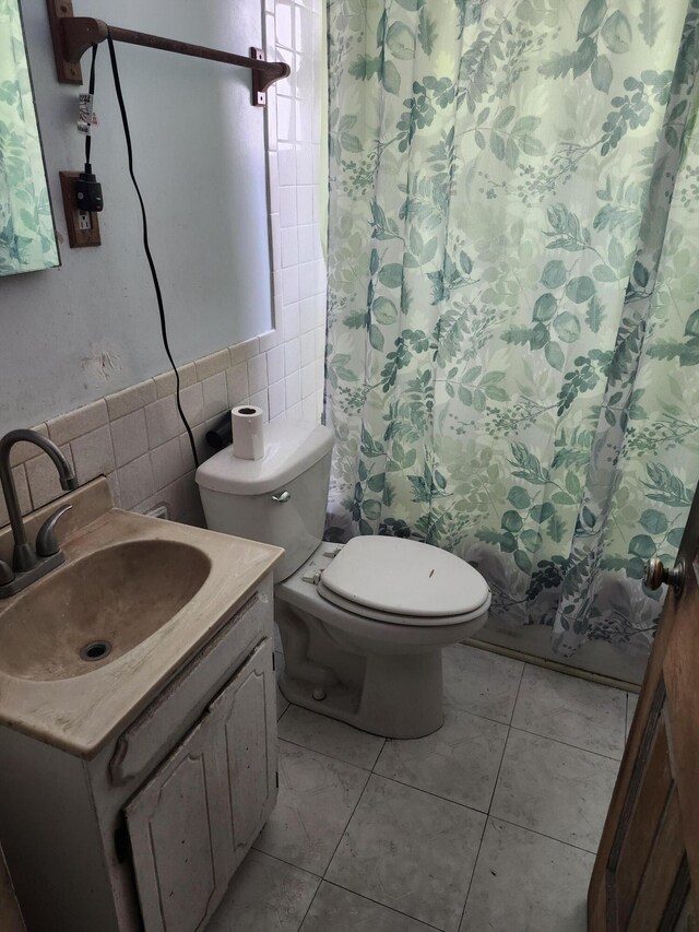 full bathroom featuring toilet, tile patterned floors, tile walls, and vanity