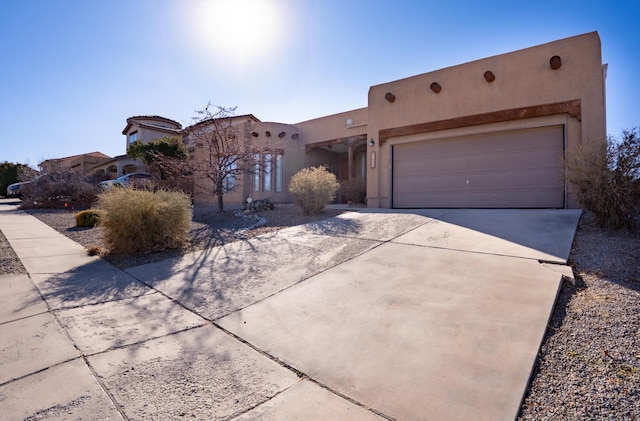 adobe home with driveway, an attached garage, and stucco siding