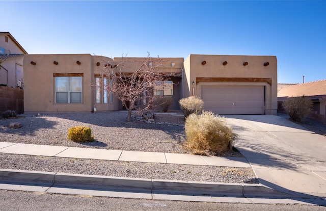 pueblo revival-style home with a garage, concrete driveway, and stucco siding