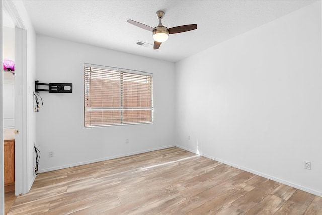 empty room with visible vents, baseboards, ceiling fan, a textured ceiling, and light wood-style floors