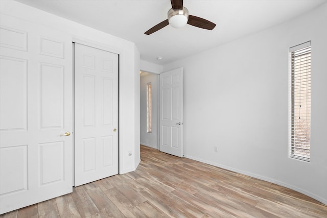 unfurnished bedroom featuring a closet, ceiling fan, light wood-style flooring, and baseboards