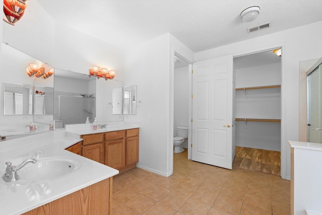 full bathroom featuring tile patterned flooring, visible vents, a sink, and a shower stall