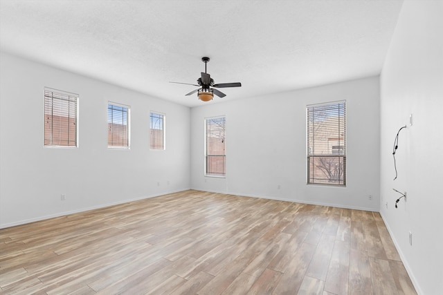 spare room with a healthy amount of sunlight, ceiling fan, a textured ceiling, and light wood finished floors