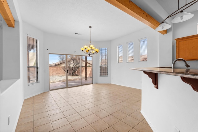 unfurnished dining area featuring a chandelier, light tile patterned floors, beam ceiling, and baseboards