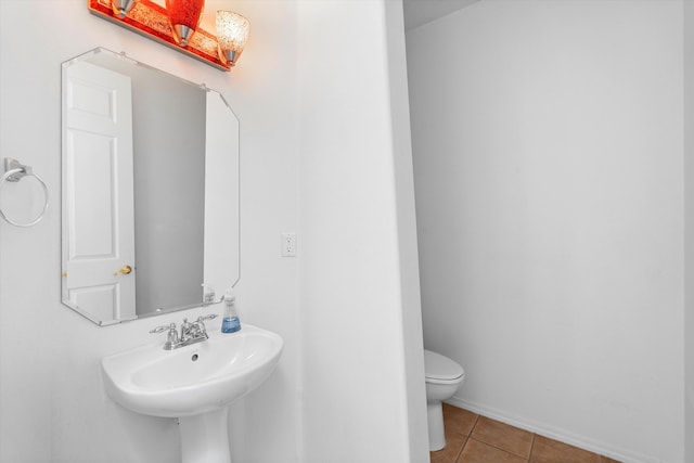 bathroom with toilet, a sink, and tile patterned floors