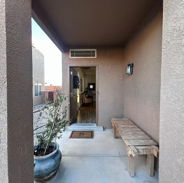 entrance to property with visible vents, a balcony, and stucco siding