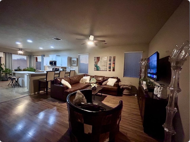 living area with ceiling fan, visible vents, and wood finished floors