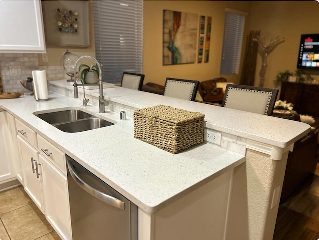 kitchen featuring decorative backsplash, a sink, light stone countertops, dishwasher, and a peninsula