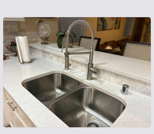 details with light stone countertops, decorative backsplash, and a sink