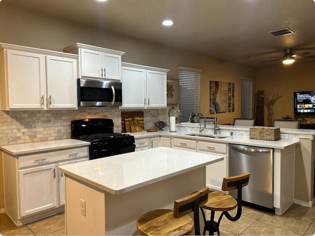 kitchen featuring decorative backsplash, ceiling fan, a peninsula, stainless steel appliances, and a sink