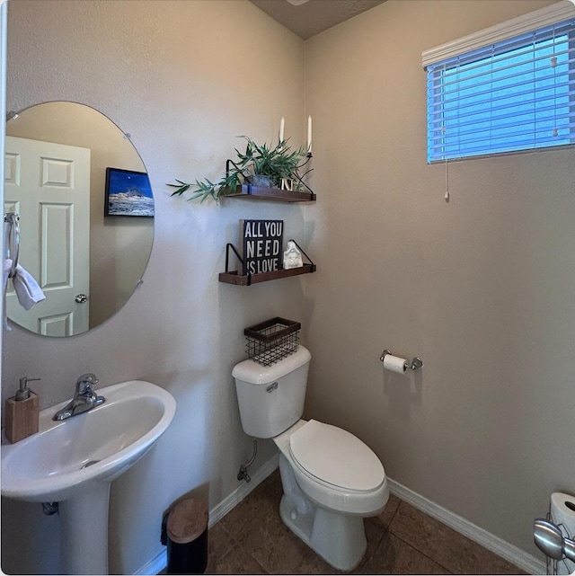 bathroom with tile patterned flooring, baseboards, a sink, and toilet