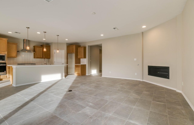 unfurnished living room featuring light tile patterned floors, recessed lighting, baseboards, and a glass covered fireplace