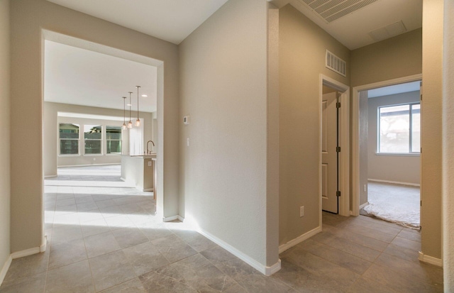 hallway featuring baseboards and visible vents