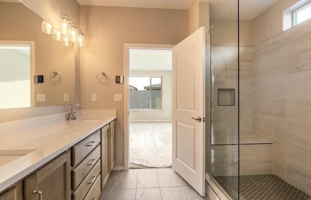 bathroom featuring double vanity, a tile shower, a sink, and tile patterned floors