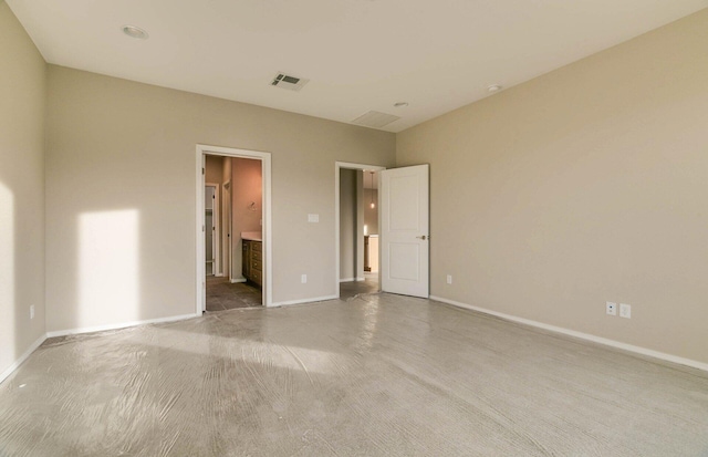 unfurnished bedroom with baseboards, visible vents, and connected bathroom