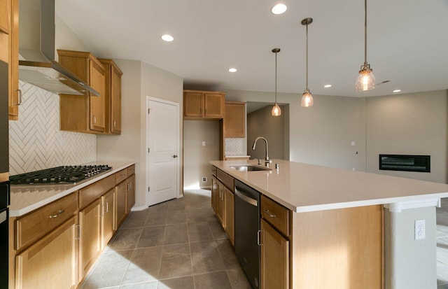 kitchen featuring recessed lighting, a sink, appliances with stainless steel finishes, brown cabinets, and wall chimney exhaust hood